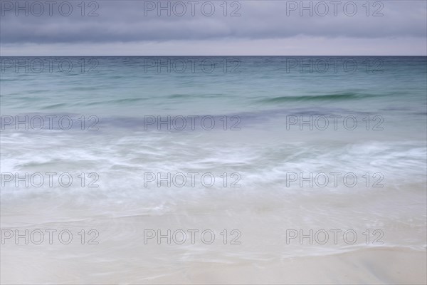 Spray and waves running on a sandy beach
