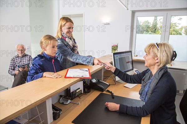 Patients filling in a form at the reception of a dental office