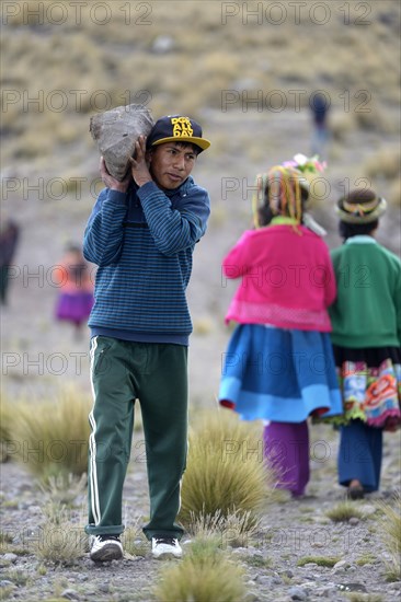 Young man carrying a heavy stone to secure the shores of an artificial lake for irrigation