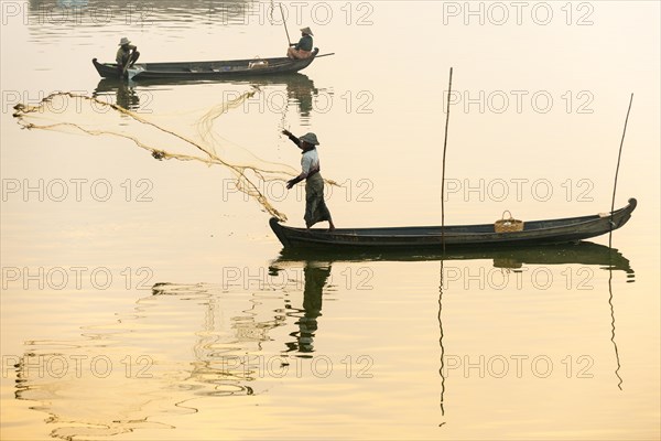 Fisherman in a boat tossing out a net