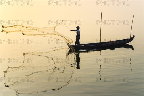 Fisherman in a boat tossing out a net