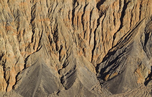 Exposed fissured bedrock of orange-colored conglomerate on the crater wall of Ubehebe Crater