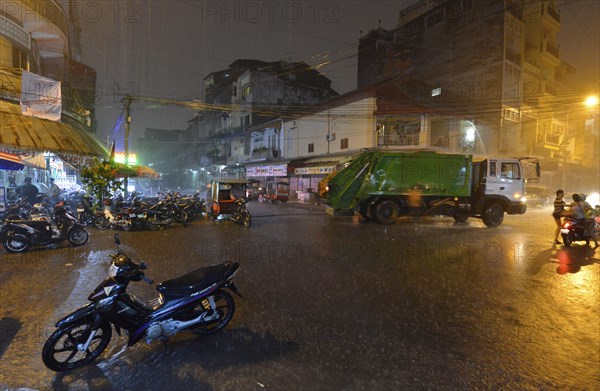 Street scene with a flooded road during heavy monsoon rain at night