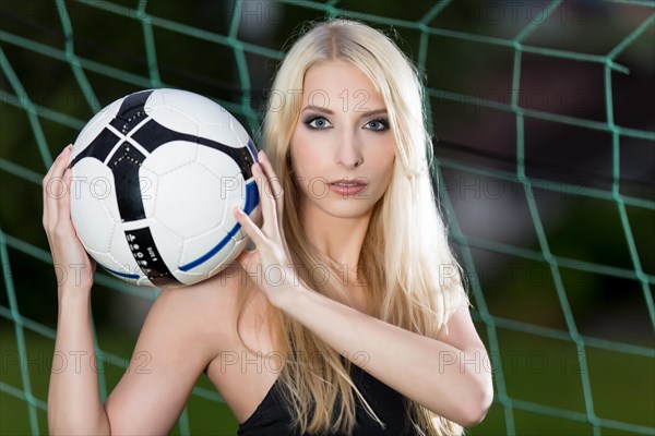 Woman posing with a football in a goal