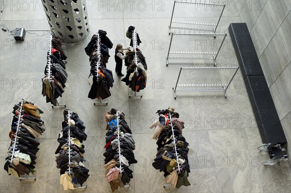 A cloakroom attendant hanging up clothes in the cloakroom at the Museum der bildenden Kunste