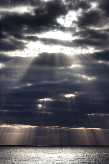 Sun rays shine through dark storm clouds