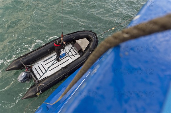 Inflatable boat being hoisted aboard an expedition ship following an excursion