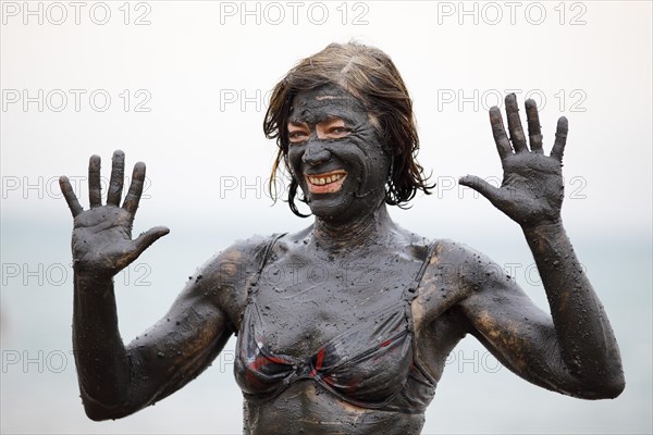 Female tourist covered in salty mud from the Dead Sea
