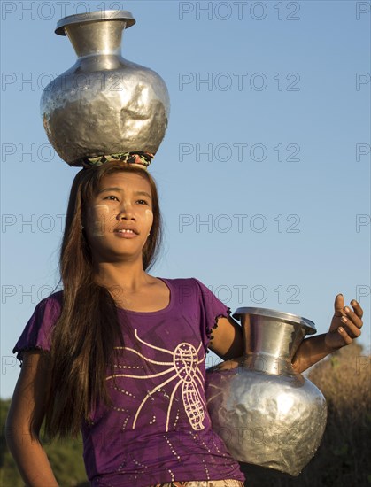 Girl with tanaka in her face carries water vessels made of aluminum