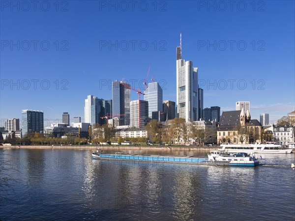 Cargo ship on the Main river in front of the skyline of Frankfurt with the buildings of Opernturm