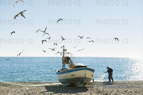 Fisherman with a fishing boat on the beach of Noli