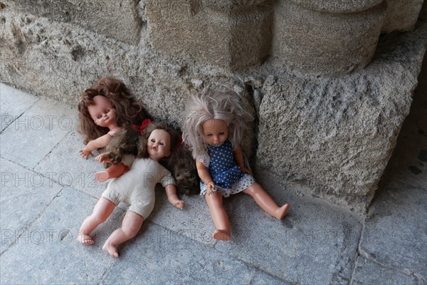 Three forgotten children's dolls beside a medieval column