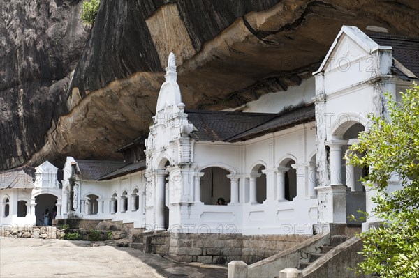 White building underneath a rock wall