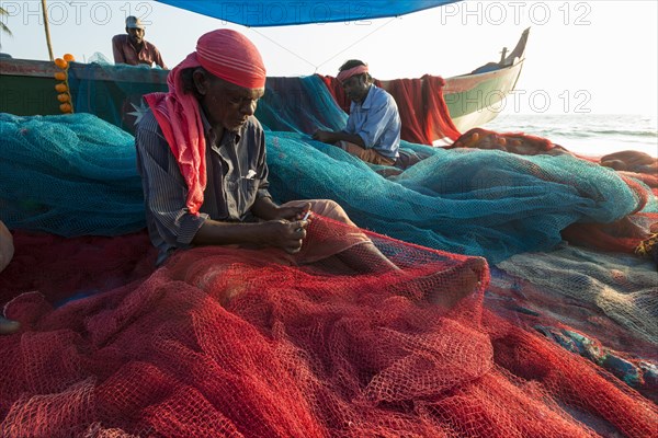 Fishermen repairing fishing nets on the beach