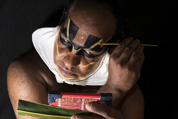 Katakali artist applying the makeup of the Shiva character