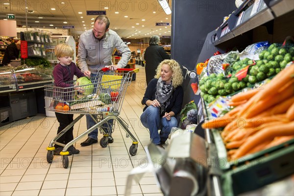Family shopping with a shopping trolley in the fruit and vegetables department of a supermarket