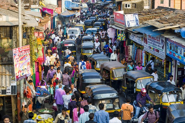 Many people and motor rikshaws causing a roadblock in a very busy market area