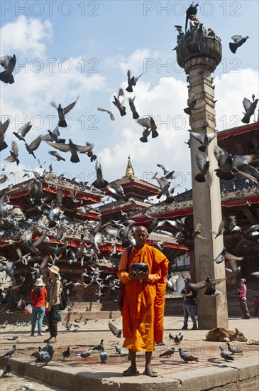 Buddhist monk with a begging bowl standing in front of Hindu temples