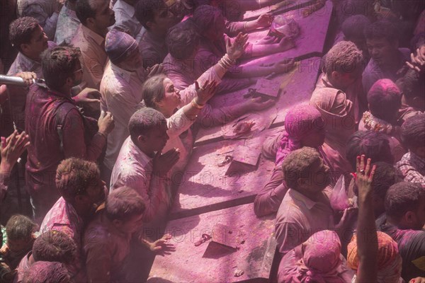 Devotees covered in coloured powder praying