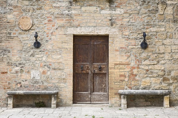 Two stone benches standing next to the door of an old house