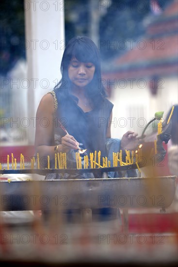 Woman lighting candles outside the Wat Phra Si Rattana Mahathat Temple
