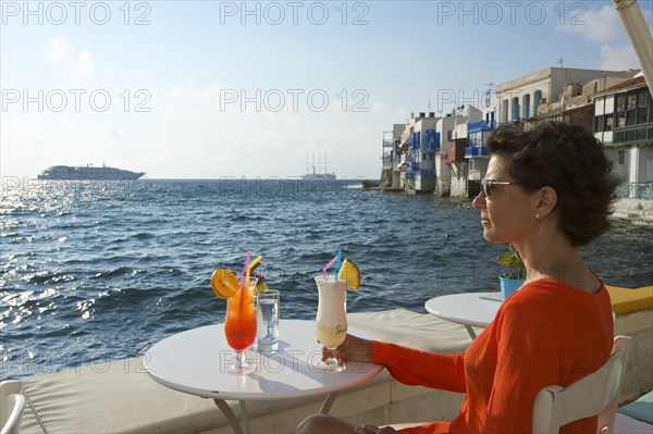 Woman enjoying a cocktail and a view over the sea