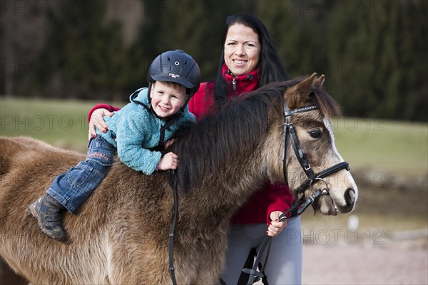 Young child wearing a riding helmet sitting bareback on a pony