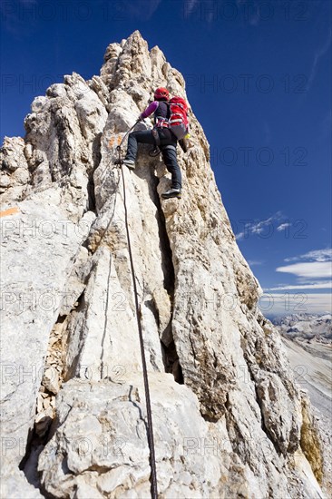 Mountain climber ascending along the Zehner Ferrata climbing route to Zehnerspitze Mountain in the Fanes Group in Fanes-Senes-Prags Nature Park