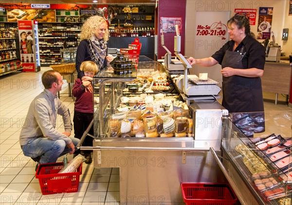 Family shopping at the cheese counter in the supermarket