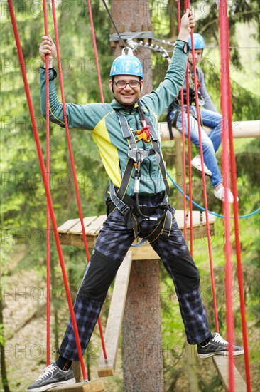 Roped up man climbing in a climbing park