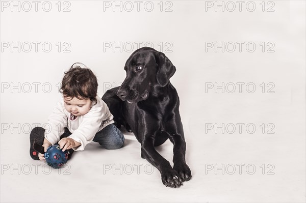 Big black mongrel lying next to a small child