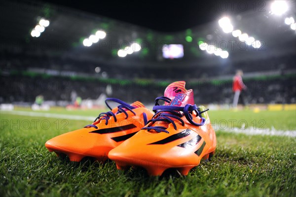 Orange-coloured Adidas football boots on the edge of the pitch