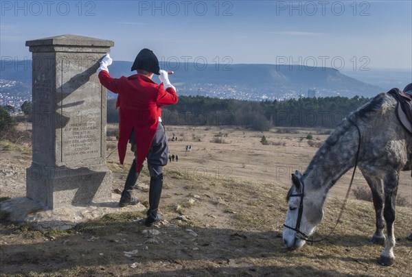 Napoleon with a telescope and horse next to his monument