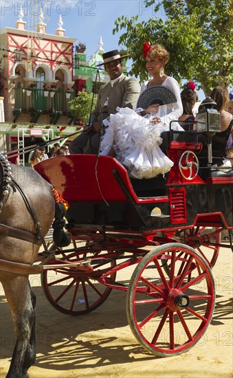 Dressed up coachman and young lady wearing a gypsy dress at the Feria del Caballo Horse Fair