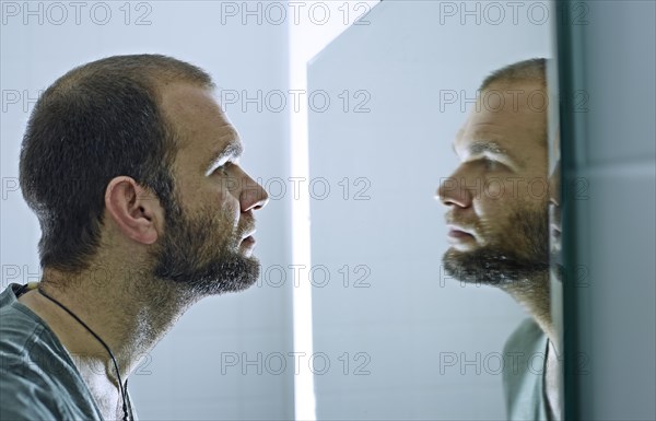 Man with a beard looking into a mirror