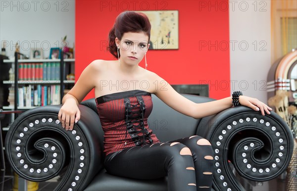 Young woman sitting on a large black armchair