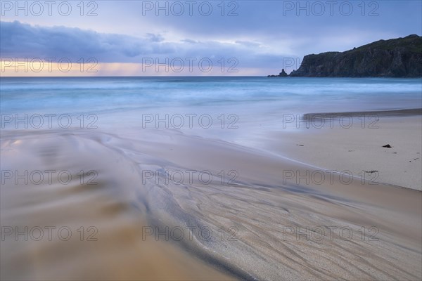 Water flows over bizarre structures on the sandy beach