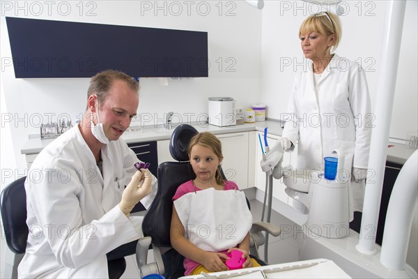 Dentist discussing further treatment with a girl and showing her braces