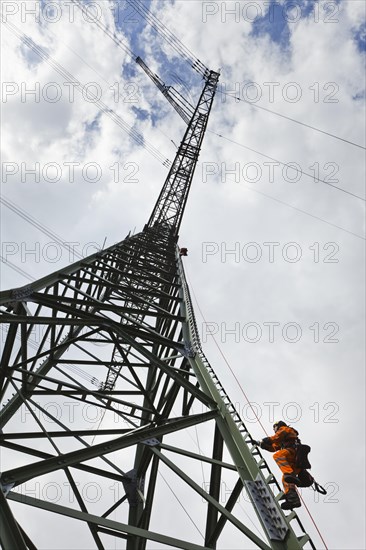 Overhead transmission cable installer climbing a mast to install insulated cable on a newly built high-voltage transmission mast