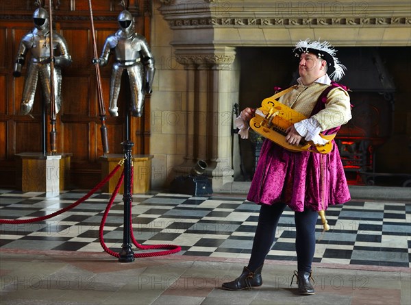 Musician in period costume performing on a medieval hurdy-gurdy