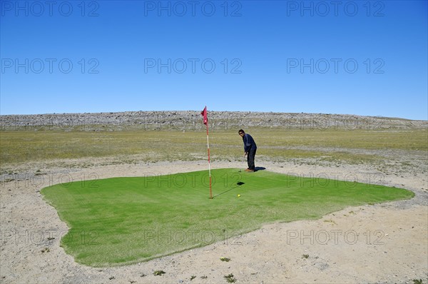 Man hitting a golf ball on the northernmost golf course in the world
