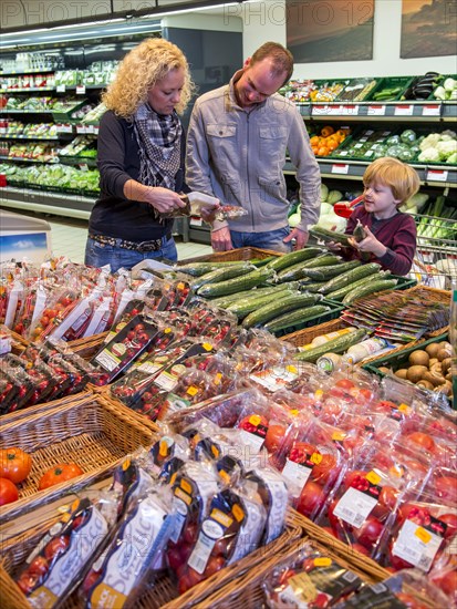 Family shopping with a shopping trolley in the fruit and vegetables department of a supermarket