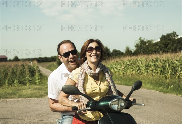 Smiling couple driving with the scooter