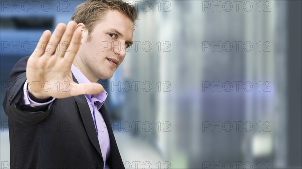 Businessman holding a hand up in a defensive manner in a subway station