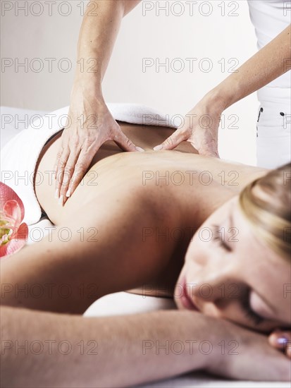 Young woman being massaged on the back by a therapist