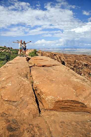 Hikers balancing on a sandstone rock in the Devil's Garden