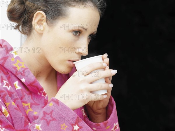 Woman wearing a bathrobe drinking coffee