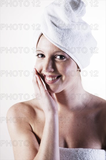 Portrait of a smiling young woman with a towel wrapped around her head