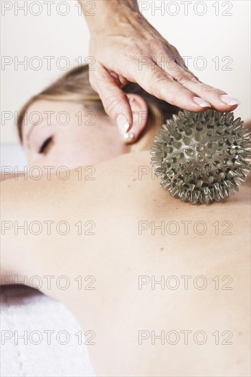 Young woman being massaged on the back with a spikey rubber massage ball