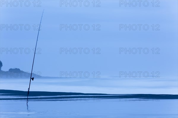 Fishing rod on the beach at dusk